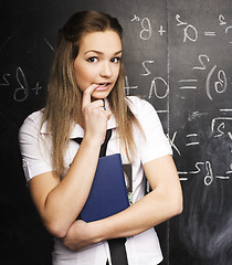 Image showing portrait of happy cute student with book in classroom at blackboard, lifestyle education people concept