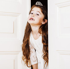 Image showing little cute girl at home, opening door well-dressed in white dre