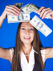 Image showing pretty young brunette real modern woman with money cash on blue background happy smiling, lifestyle people concept