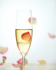 Image showing glass of champagne and falling rose petals