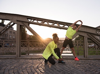 Image showing jogging couple warming up and stretching in the city