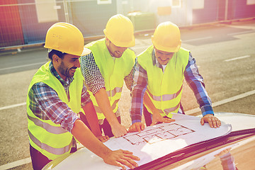 Image showing close up of builders with blueprint on car hood