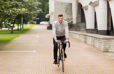 Image showing young man riding bicycle on city street