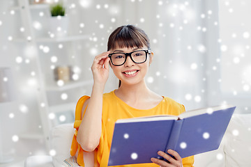 Image showing smiling young asian woman reading book at home