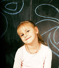 Image showing little cute girl in classroom at blackboard writing smiling, preschooler from back alone, lifestyle people concept