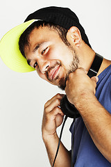 Image showing young asian man in hat and headphones listening music on white b