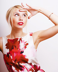 Image showing young pretty blonde girl presenting something at white copy space, emotional posing, lifestyle people concept