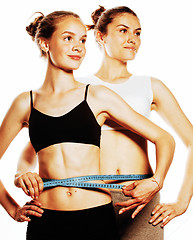 Image showing two sport girls measuring themselves isolated on white