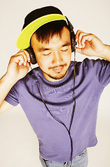 Image showing young asian man in hat and headphones listening music on white b