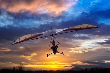 Image showing Motorized hang glider flying in the sunset