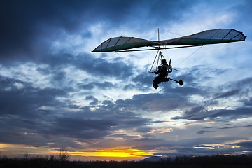 Image showing Motorized hang glider flying in the sunset