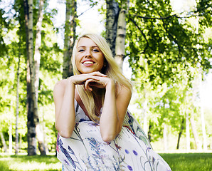 Image showing happy blond young woman in park smiling, floral close up