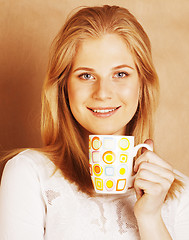 Image showing young cute blond girl drinking coffee close up on warm brown bac