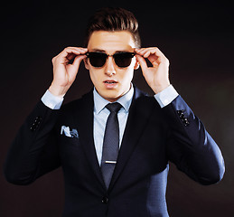 Image showing young pretty business man standing on black background, modern h