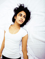 Image showing young pretty tan indian mulatto woman in bed among white sheets having fun, trying to sleep, lifestyle people concept