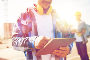 Image showing close up of builder with headphones and tablet pc