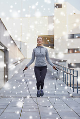 Image showing happy woman exercising with jump-rope outdoors