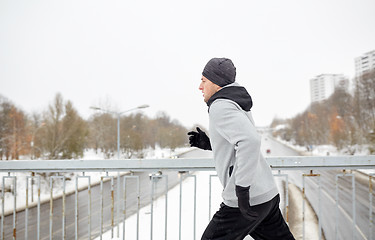 Image showing man running along snow covered winter bridge road