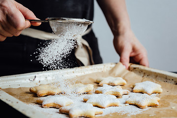 Image showing Person covering cookies with powdered sugar