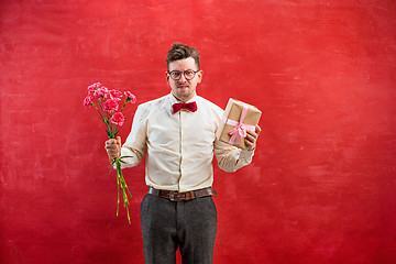 Image showing Young funny man with flowers and gift