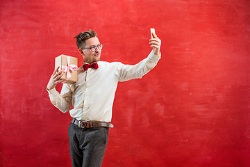 Image showing Young beautiful man with gift and phone