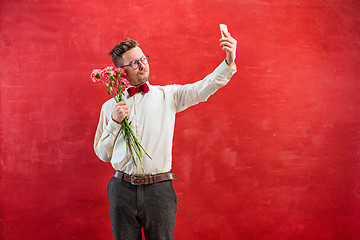 Image showing Young beautiful man with flowers and phone