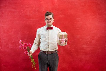 Image showing Young funny man with flowers and gift