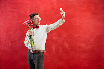 Image showing Young beautiful man with flowers and phone