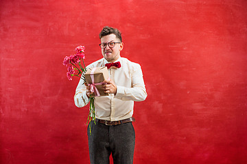 Image showing Young funny man with flowers and gift