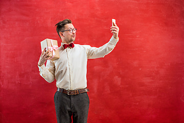 Image showing Young beautiful man with gift and phone