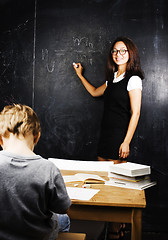 Image showing little cute boy with young teacher in classroom studying at blac