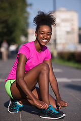 Image showing African american woman runner tightening shoe lace