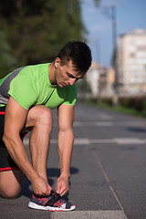 Image showing Young athlete, runner tie shoelaces in shoes