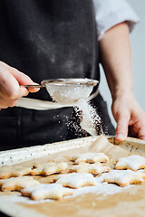 Image showing Person covering cookies with powdered sugar