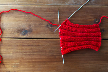 Image showing hand-knitted item with knitting needles on wood