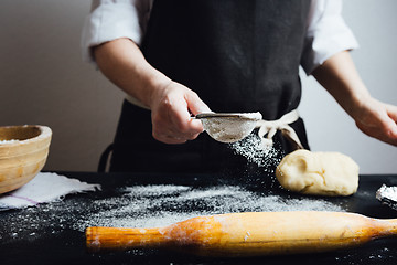 Image showing Cook covering table with flour