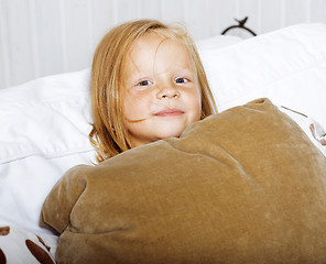 Image showing little cute blonde norwegian girl playing on sofa with pillows, lifestyle people concept