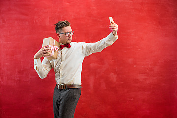 Image showing Young beautiful man with gift and phone