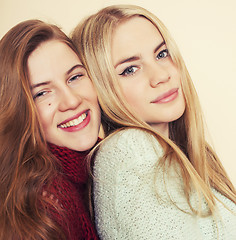 Image showing Two young girlfriends in winter sweaters indoors having fun. Lifestyle. Blond teen friends close up