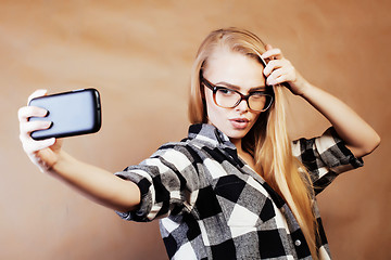 Image showing young pretty blond hipster girl making selfie on warm brown back