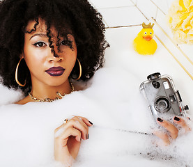 Image showing young afro-american teen girl laying in bath with foam, wearing 