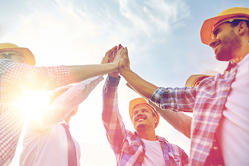 Image showing close up of builders in hardhats making high five