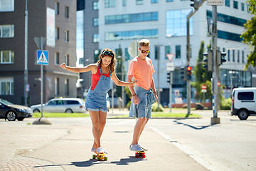 Image showing teenage couple riding skateboards on city street
