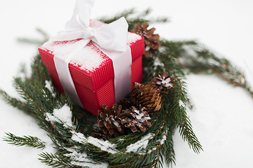 Image showing christmas gift and fir wreath with cones on snow