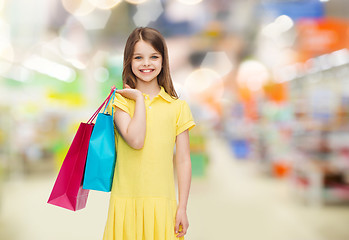 Image showing smiling girl with shopping bags over supermarket