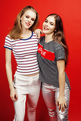 Image showing two best friends teenage girls together having fun, posing emotional on red background, besties happy smiling, lifestyle people concept