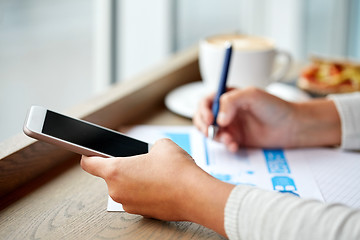 Image showing woman with smartphone and chart at cafe