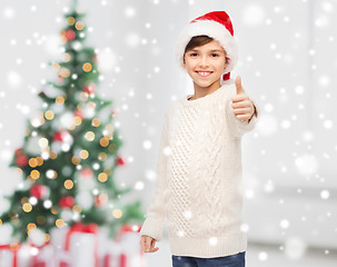 Image showing smiling happy boy in santa hat showing thumbs up