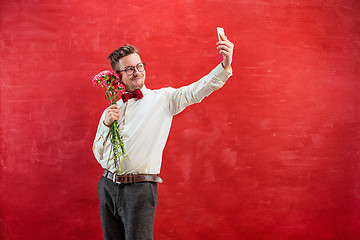 Image showing Young beautiful man with flowers and phone