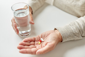 Image showing close up of old man hands with pills and water